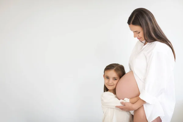 Jovem mulher grávida bonita e sua filha pequena — Fotografia de Stock