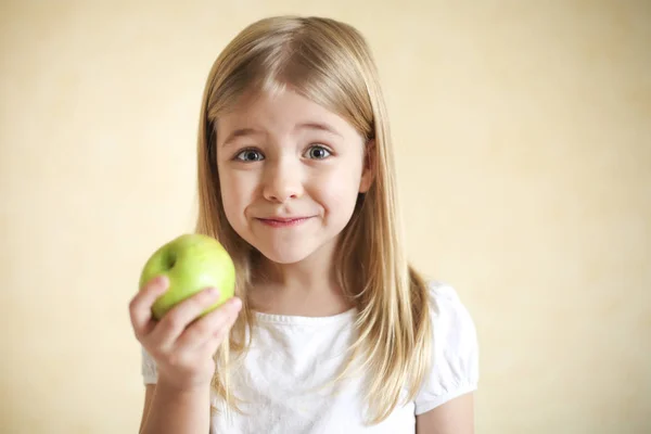 Маленькая смешная блондинка с зеленым яблоком — стоковое фото
