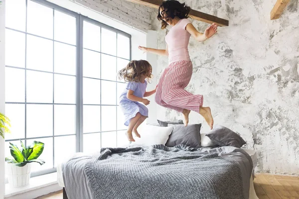 Diversão familiar. Mãe e filha pulando na cama — Fotografia de Stock