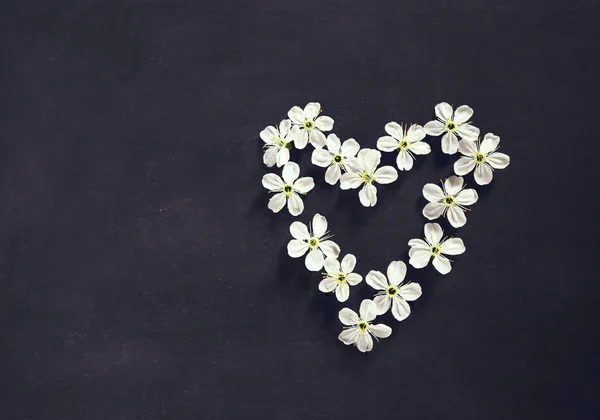 White flowers in shape of heart on black background — Stock Photo, Image