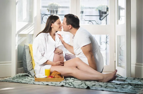 Pregnant woman and man having breakfast with orange juice near w — Stock Photo, Image