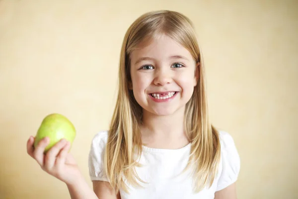 Piccola ragazza bionda divertente con mela verde — Foto Stock