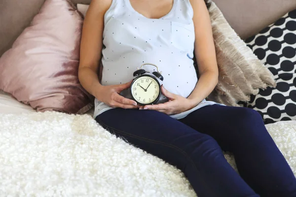 Schwangere im Haus auf dem Bett sitzend — Stockfoto