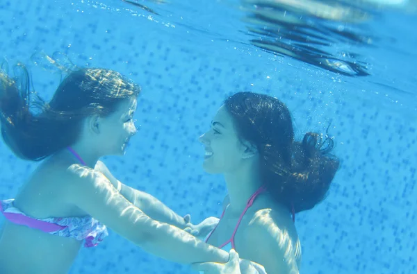 Kleines Kind und junge Frau unter Wasser im Schwimmbad — Stockfoto