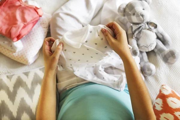Mulher grávida está embalando roupas de bebê — Fotografia de Stock