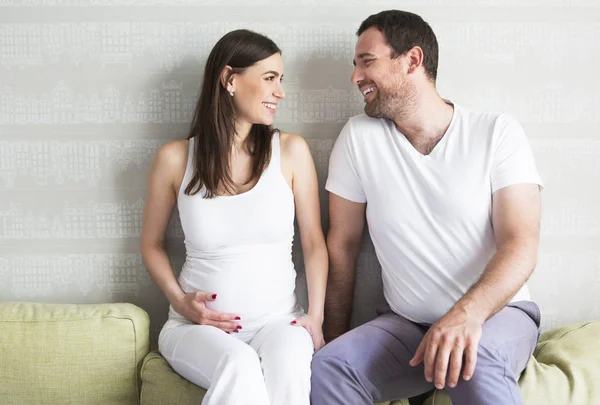 Zwangere vrouw en jonge man samen binnenshuis — Stockfoto