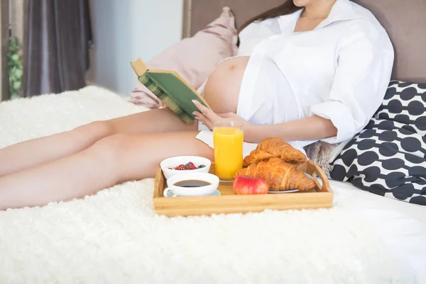 Mujer embarazada desayunando con café, jugo de naranja, crois — Foto de Stock