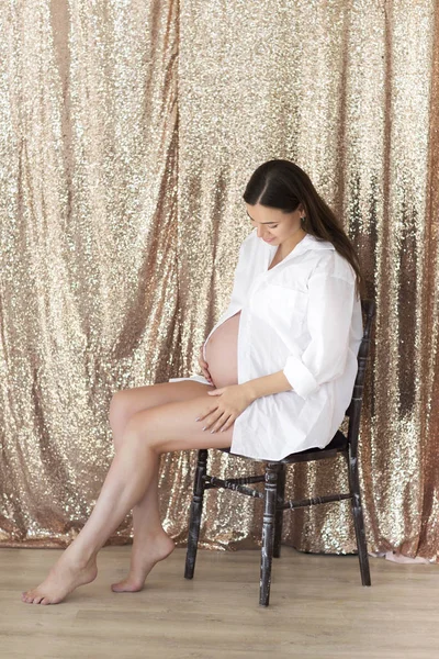 Zwangere vrouw binnenshuis zittend op de stoel — Stockfoto