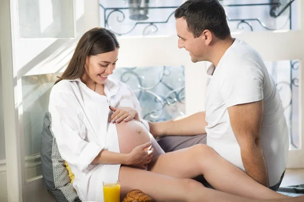 Pregnant woman and man having breakfast with orange juice near w — Stock Photo, Image