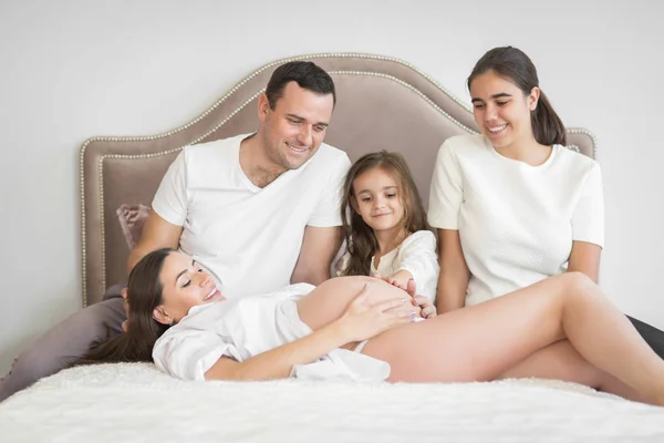 Šťastná žena těhotná se svým manželem a dětmi — Stock fotografie