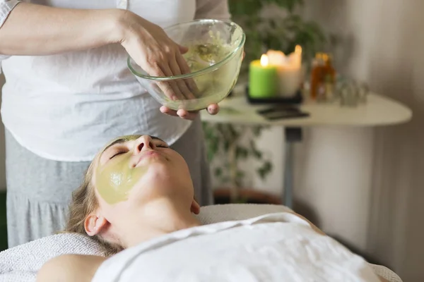 Hermosa mujer relajada que tiene mascarilla de arcilla en el salón de spa —  Fotos de Stock