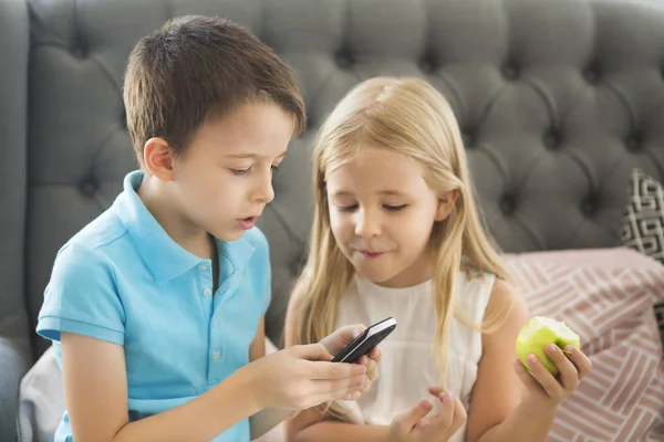 Broertje en zusje op de Bank spelen mobiele telefoon toget — Stockfoto