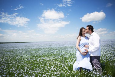 Genç mutlu, güzel, hamile bir çift keten tarlasında