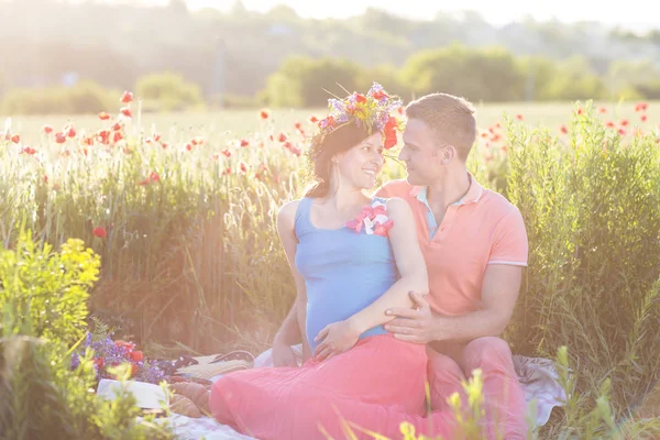 Fiatal szép terhes pár a mák mező — Stock Fotó