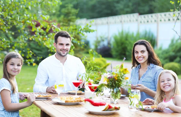 Familia feliz de cuatro personas disfrutando de la comida juntos al aire libre — Foto de Stock