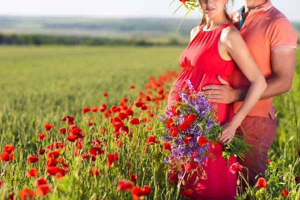 Young beautiful pregnant couple in poppy field — Stock Photo, Image