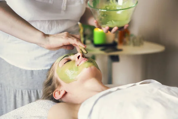 Bella donna rilassata con maschera viso in argilla nel salone spa — Foto Stock
