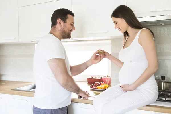 Pregnant woman and happy man in the kitchen — Stock Photo, Image