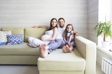 Sevimli genç hamile aile oturma odasında. 