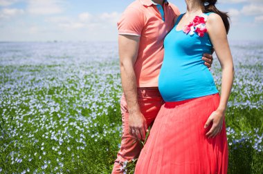 Genç güzel hamile çift keten alanda