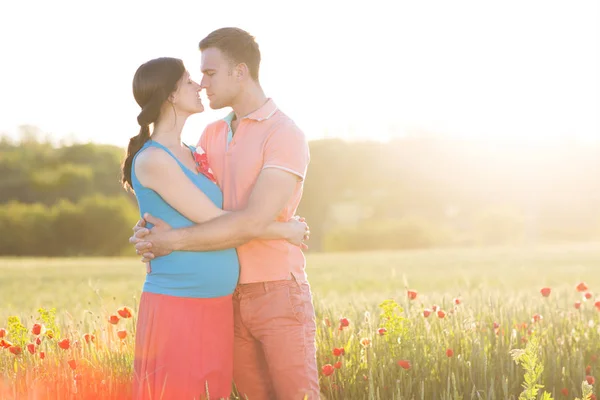 Young beautiful pregnant couple in poppy field — Stock Photo, Image