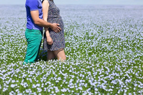 Young happy beautiful pregnant couple in linen field — Stock Photo, Image