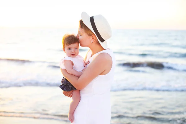 Mooie jonge vrouw met baby op het strand — Stockfoto