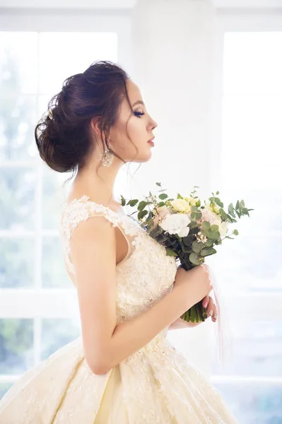 Bella donna bruna con bouquet in posa in un abito da sposa — Foto Stock