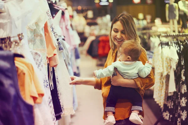 Mujer rubia con hija pequeña en tienda de ropa — Foto de Stock