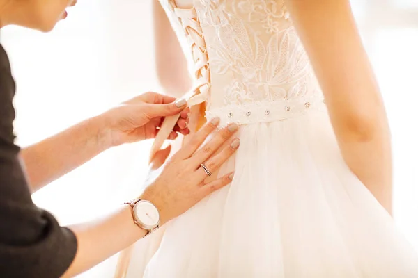 Demoiselle d'honneur aider la mariée à mettre sa robe de mariée sur — Photo