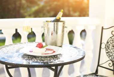 Şampanya şişesi ith gözlük ve tatlı masada