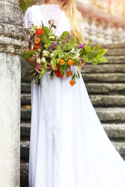 Mulher loira com buquê posando em um vestido de noiva. Fechar — Fotografia de Stock