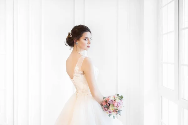 Bella donna bruna con bouquet in posa in un abito da sposa — Foto Stock