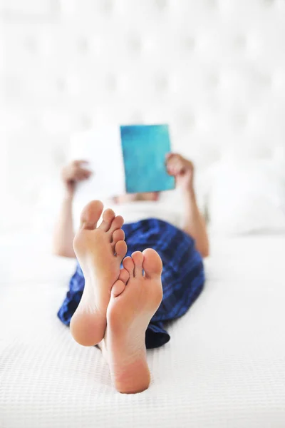 Young man reading book in the bed — Stock Photo, Image