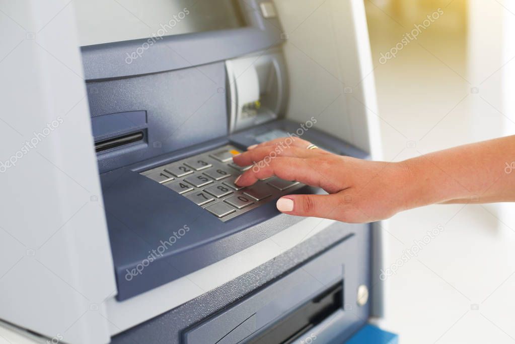 Young tourist woman using banking machine 