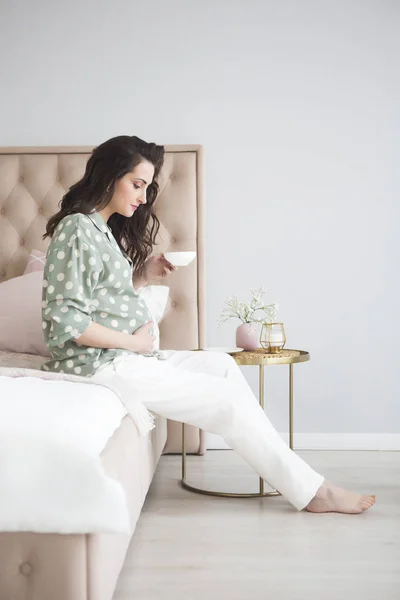 Enceinte jeune femme heureuse buvant du thé au lit — Photo