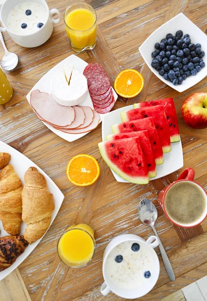 Koffie met fruit, cornflakes en croissant op houten tafelblad — Stockfoto