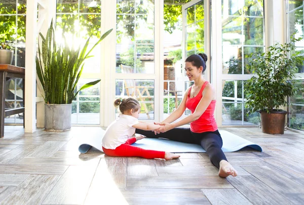 Jonge brunette vrouw met kleine dochter in een sportieve uniform do — Stockfoto