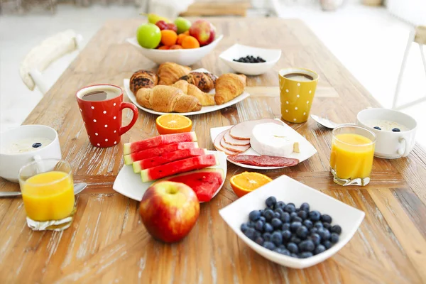 Koffie met fruit, cornflakes en croissant op houten tafelblad — Stockfoto