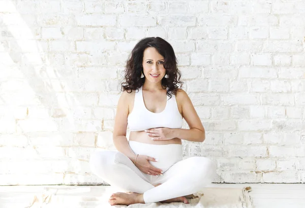 Hermosa mujer embarazada estirándose y practicando yoga en casa —  Fotos de Stock