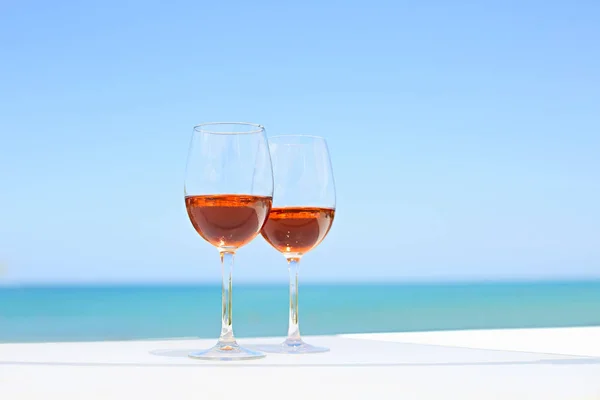 Dois copos de vinho rosa contra água azul e mar — Fotografia de Stock