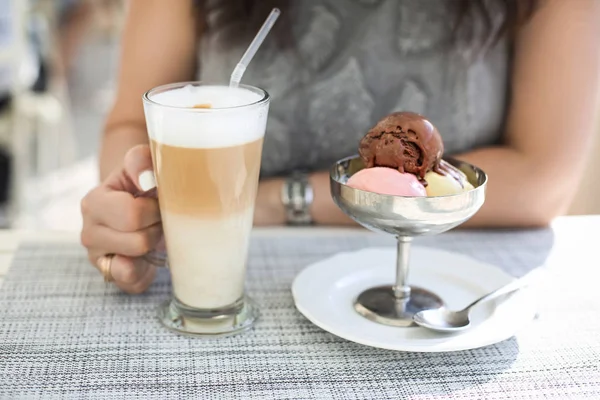 Mujer bebiendo café con leche y comiendo helado en la cafetería al aire libre — Foto de Stock