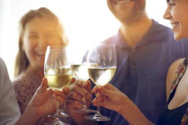 Beyaz şarapla tezahürat yapan bir grup insanın elleri.