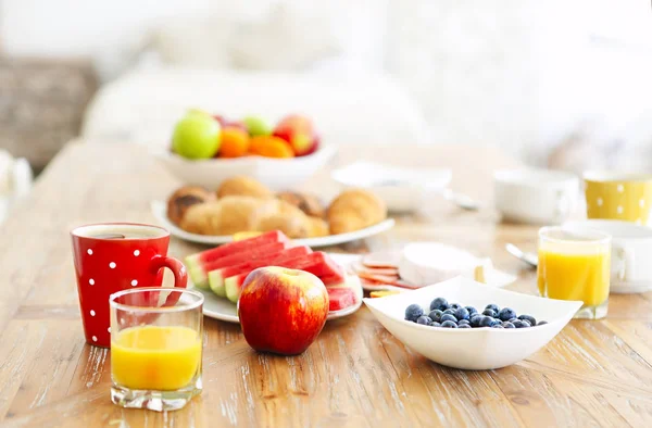 Coffee with fruit, cereal and croissant on wooden table backgrou