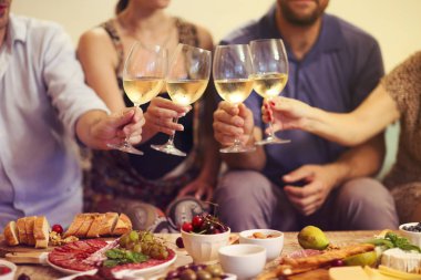 Beyaz şarapla tezahürat yapan bir grup insanın elleri.