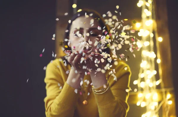 Happy beautiful brunette girl wearing yellow sweater blowing on — Stock Photo, Image