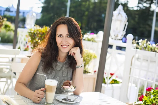 Donna che beve caffè macchiato e mangia gelato in un caffè all'aperto — Foto Stock