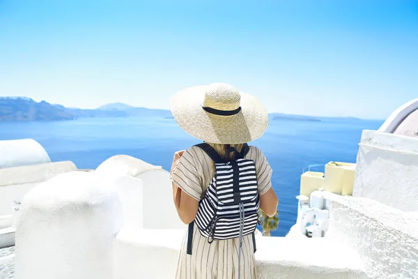 Νεαρή γυναίκα με λευκό φόρεμα και ψάθινο καπέλο, να περπατάει στην πόλη — Φωτογραφία Αρχείου