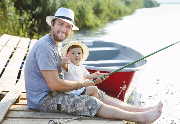 Ojciec z małym synem łowiącym ryby na brzegu rzeki — Zdjęcie stockowe