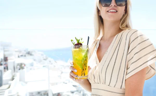 Woman holding a glass of passion fruit cocktail in Santorini bac — 스톡 사진